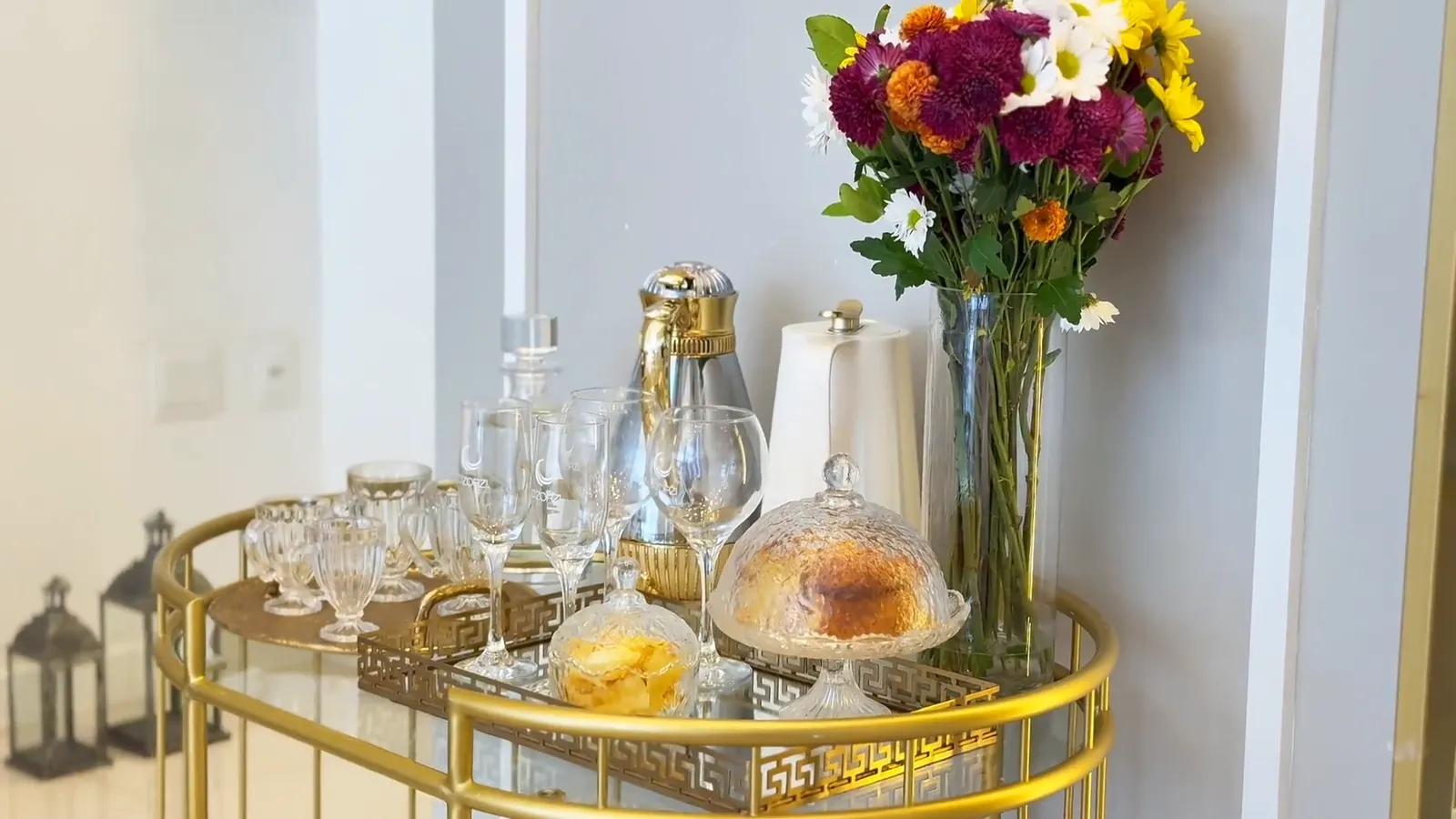 Carrinho dourado da recepção com flores, taças e jarra de vidro