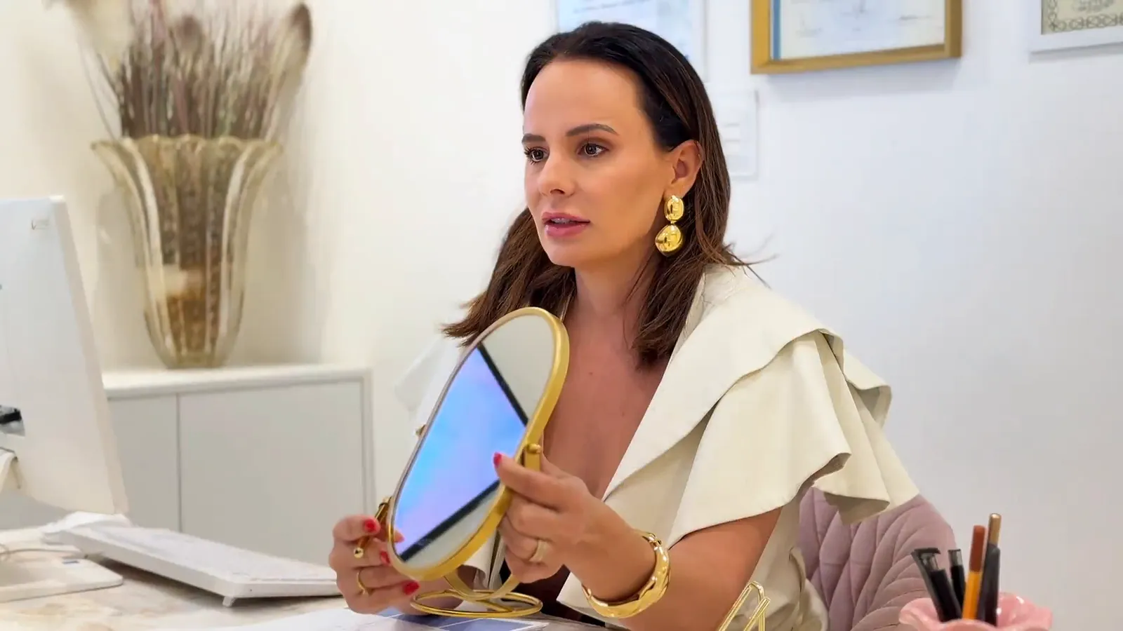 Aline de Zorzi na mesa de atendimento, com um espelho de mão