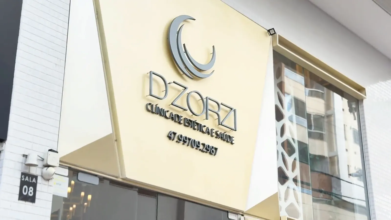 O letreiro D'Zorzi Clínica de Estética e Saúde na entrada, com a placa da Sala 08